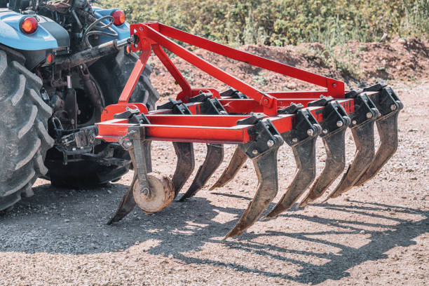 a plow for cultivating the soil is attached to a dusty tractor. Equipment in industry of agriculture